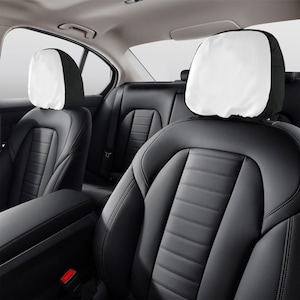 Puede incluir: Dos asientos de coche de cuero negro con reposacabezas blancos. Los asientos tienen un patr&oacute;n de diamante y est&aacute;n en el interior de un coche.