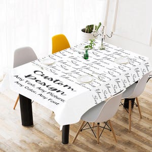 Puede incluir: Mantel blanco de diseño personalizado con texto negro que dice "Say Your Loves" y "Custom Design". El mantel está sobre una mesa con patas negras, rodeada de sillas blancas y amarillas. El texto del mantel se puede personalizar.
