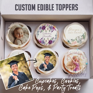 May include: A box of cupcakes with custom edible toppers. The toppers feature images of a baby, a graduate, and floral designs with text. The box also contains text that reads "Cupcakes, Cookies, Cake Pops, & Party Treats."
