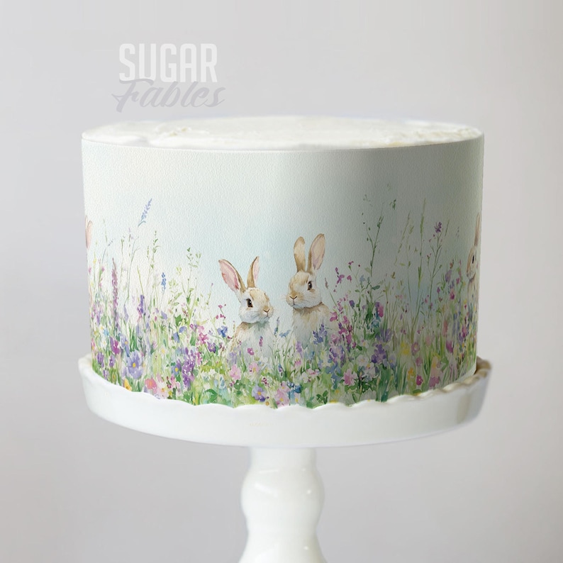 A cake decorated with a floral design featuring two rabbits in a meadow.
