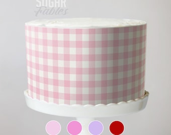 Puede incluir: Un pastel redondo con un patrón de cuadros rosa y blanco, exhibido en un soporte blanco para pasteles. El pastel está decorado con el texto "Sugar Fables" en una fuente cursiva. Se muestran cuatro muestras de color debajo.