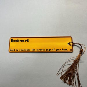 May include: A gold bookmark with the text "Bookmark" and "Used to remember the current page of your book."  The bookmark has a brown tassel.