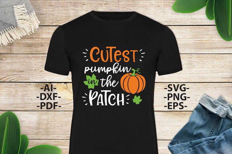 May include: A black short-sleeved t-shirt featuring the orange and white text "CUTEST pumpkin in the PATCH" with a graphic of an orange pumpkin and green leaves. The text "AI-DXF-PDF" and "SVG-PNG-EPS" is printed on the sides of the shirt.