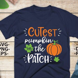 May include: A navy blue t-shirt featuring the orange and white text "CUTEST pumpkin in the PATCH" with a graphic of an orange pumpkin and two green leaves. The text "SVG", "PNG", "EPS", "AI", "DXF", and "PDF" is printed on the sides.