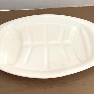 May include: White oval serving dish with blue floral accents on each end. The dish has a divided interior and is made of ceramic. A vintage piece for serving food.