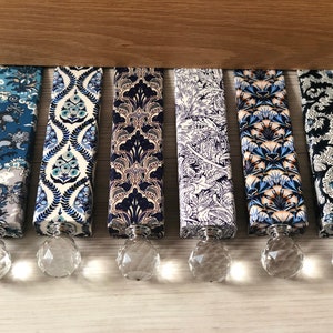 May include: Six decorative cabinet pulls with patterned fabric in blue and white, and faceted crystal knobs. The fabric designs include floral and abstract patterns. Each pull is approximately 15 cm long.