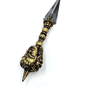 Puede incluir: Una daga ceremonial de oro y plata con un mango detallado y adornado. La hoja es afilada y puntiaguda.