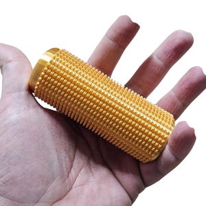 May include: A gold-coloured, textured roller with a cylindrical shape. The roller is covered in small, raised bumps.