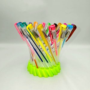 May include: A bright green pen holder with a spiral design holds a variety of colorful gel pens. The pens are arranged in a fan shape, with the tips of the pens pointing upwards.