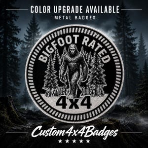 May include: A circular metal badge featuring a black and silver design with a central illustration of a Bigfoot creature standing in a forest. The text reads "BIGFOOT RATED" and "4x4" in bold lettering. The top text states "COLOR UPGRADE AVAILABLE".