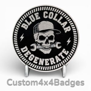 May include: A round, black and silver metal badge with the words "BLUE COLLAR DEGENERATE" around the edge. The center features a skull wearing a cap and holding a wrench in its teeth. Two lightning bolts flank the skull.