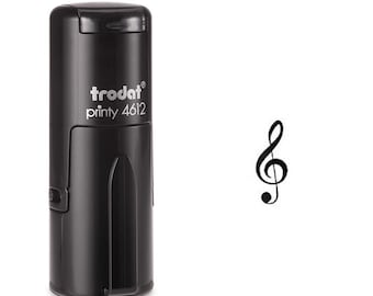 May include: A black self-inking stamp with the text "trodat printy 4612" printed on the side. The stamp is next to a black treble clef symbol on a white background. The stamp is designed for musical notation.