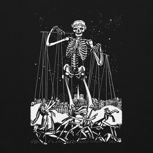 May include: A black and white graphic print featuring a large skeleton wearing a floral crown, acting as a puppeteer. The skeleton controls several human figures below with strings against a starry night sky and a detailed city skyline background.
