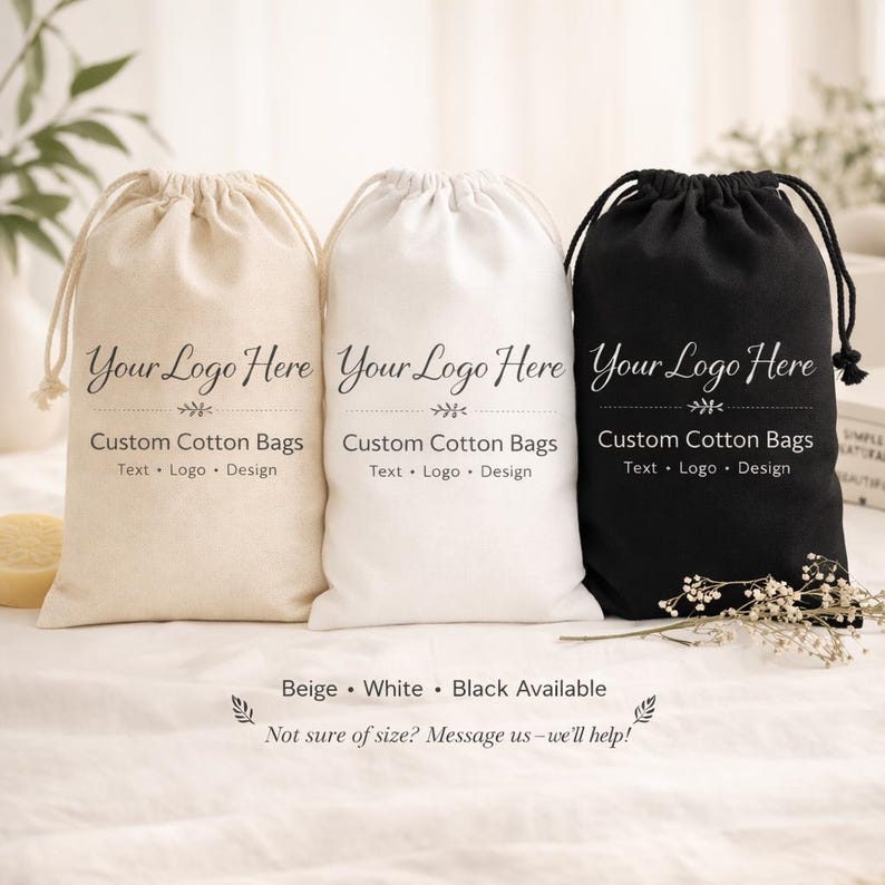 May include: Three custom cotton drawstring bags in beige, white, and black. Each bag features the text "Your Logo Here" above "Custom Cotton Bags" and "Text &bull; Logo &bull; Design". The bags are displayed on a white surface.