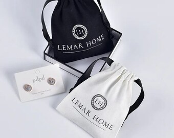 May include: Two white cotton drawstring bags with black ribbon ties. Both bags have the logo "Lemar Home" and a stylized "LH" monogram printed in black.