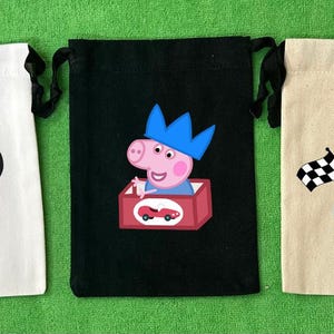 May include: Three drawstring bags with different designs. The first bag is white with a red and white polka dot bow and a black and white cartoon mouse face. The second bag is black with a pink pig wearing a blue crown and holding a red toy car. The third bag is beige with a blue race car with a checkered flag and the number 3 on the side.