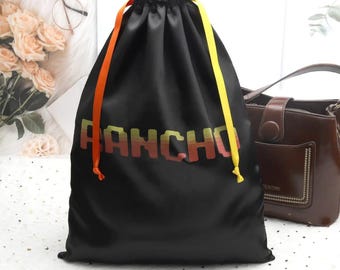 May include: Black drawstring bag with yellow and orange drawstrings and the word "RANCHO" printed in yellow, orange, and red letters.