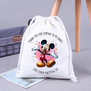 May include: White drawstring bag with a Mickey Mouse design. The bag has the text "Thank you for coming to my party" and "Love from Matthew XX".