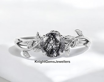 May include: A silver ring featuring an oval-cut black rutilated quartz gemstone. The ring has a leaf and vine design with small, clear accent stones. The text "KnightGemsJewellers" is visible.