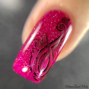 Pu&ograve; includere: Primo piano di un'unghia rosa con un design a spirale nero. Lo smalto ha una finitura glitter.