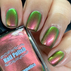 May include: A close-up of a bottle of nail polish with a green and pink iridescent finish. The bottle is labeled "Nail Polish" and "Cosmetics".