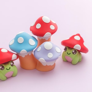 May include: A collection of whimsical mushroom figurines in red, blue, and purple with white polka dots. The mushrooms sit atop tan stems, and two have smiling frog faces. The background is a soft pink.