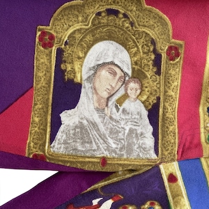 Könnte beinhalten: Ein violetter, roter und blauer Stoff mit einem goldgerahmten Bild der Jungfrau Maria und des Jesuskindes. Das Bild ist von einem goldenen Rahmen mit aufwendigen Details umgeben.