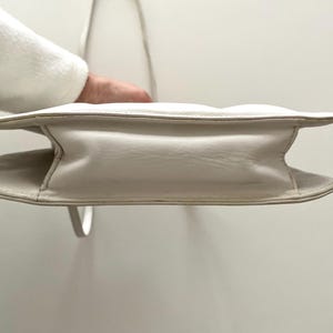 Pode incluir: Uma bolsa de m&atilde;o de couro branco com um design acolchoado e uma al&ccedil;a superior.