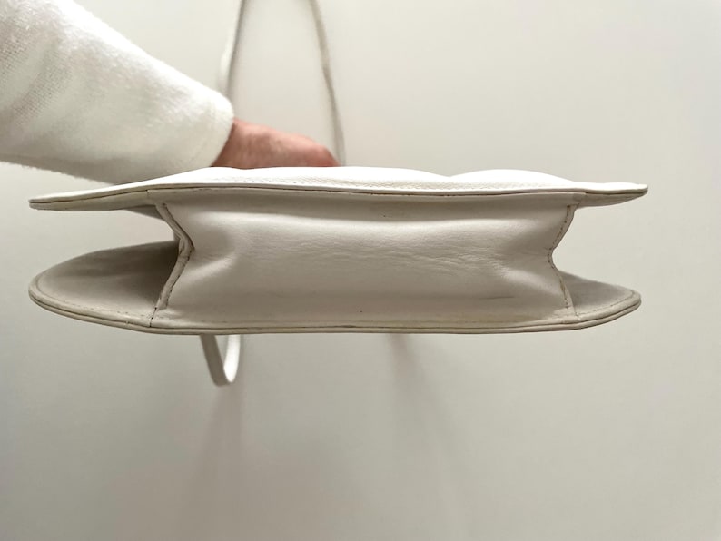 Pode incluir: Uma bolsa de m&atilde;o de couro branco com um design acolchoado e uma al&ccedil;a superior.