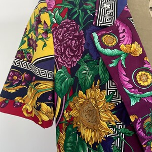 May include: A colorful blazer with a vibrant floral pattern featuring sunflowers, peonies, and other flowers in shades of yellow, purple, and red. The blazer has a unique design with a mix of patterns and colors, perfect for a bold fashion statement.