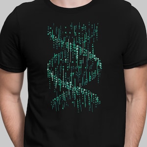 Op de afbeelding: Zwart T-shirt met een groen en blauw grafisch ontwerp van een schedel gemaakt van code. De code bevat Japanse karakters.