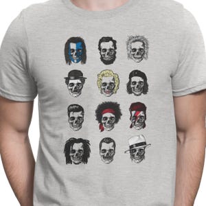 Könnte beinhalten: Ein graues T-Shirt mit einem Grafikdruck von 12 verschiedenen Schädel-Designs. Jeder Schädel hat eine einzigartige Frisur und Gesichtszüge.