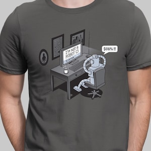 Könnte beinhalten: Ein graues T-Shirt mit einem Roboter, der an einem Schreibtisch vor einem Computerbildschirm sitzt. Der Computerbildschirm zeigt den Text "Ich bin kein Roboter". Der Roboter sagt "$%&!!!".
