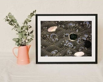 Puede incluir: Una impresión artística enmarcada con un marco negro. La obra de arte presenta un patrón de olas en negro y dorado con formas abstractas en blanco, verde y negro. A la izquierda, una jarra rosa con hojas verdes.