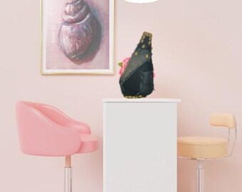 Puede incluir: Una obra de arte enmarcada de una concha marina en tonos morados y rosas cuelga de una pared rosa. Un jarrón decorativo negro y dorado con flores rosas se encuentra sobre un pedestal blanco. Dos sillas rosas y beige están en primer plano.