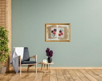 Puede incluir: Escena interior con una obra de arte enmarcada con diseños florales en tonos rojos y morados. Una silla moderna con asiento negro y una manta blanca está cerca de una pequeña mesa de madera con un jarrón de flores moradas. También se ven una planta en maceta y persianas de madera.
