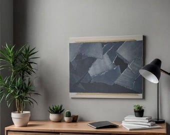 Puede incluir: Obra de arte abstracta con un diseño geométrico en tonos azules y grises, enmarcada con un borde beige claro y detalles dorados. La obra cuelga sobre un escritorio de madera con plantas y una lámpara de escritorio negra.