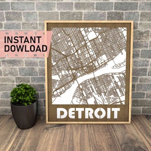 May include: A brown wood framed print of a map of Detroit, Michigan. The map is cut out of the wood, creating a 3D effect. The word "DETROIT" is printed in white letters at the bottom of the print.