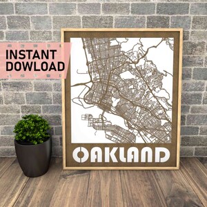 May include: A digital download of a laser cut map of Oakland, California. The map is in a brown frame and the city name is written in white letters below the map.