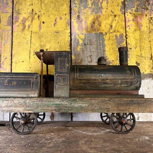 May include: A vintage wooden toy train painted in black and green. The train has a caboose with the letters "C.R." on the side. The train has four wheels and is on a wooden track.