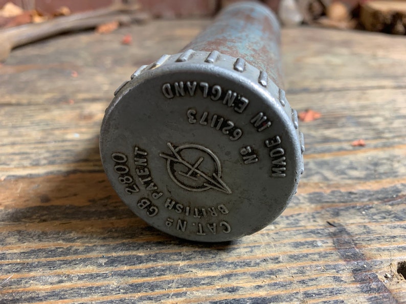 May include: A silver metal grease gun with a black cap. The cap has the text "CAT. NO. 62113 MADE IN ENGLAND" and "BRITISH PATENT GB 2800".