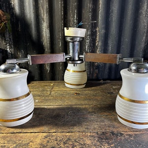 May include: A vintage three-light ceiling fixture with white glass shades featuring gold stripes and wooden arms.