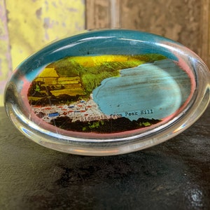 Könnte beinhalten: Ein durchsichtiger Glas-Briefbeschwerer mit einem Vintage-Postkartenbild darin. Die Postkarte zeigt eine Ansicht von Sidmouth vom Peak Hill.