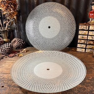 May include: Two clear glass ceiling light fixtures with a decorative pattern. The fixtures are round and have a central hole for a light bulb.