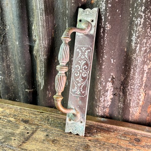 May include: Antique brass door handle with an ornate design. The handle has a decorative, twisted design and a backplate with a floral pattern.
