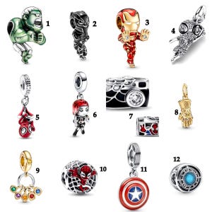 May include: Collection of superhero-themed charms. Includes Hulk, Black Panther, Iron Man, Spider-Man, Captain America, and other characters. Charms are silver, gold, red, black, and green. Some charms feature a camera design.