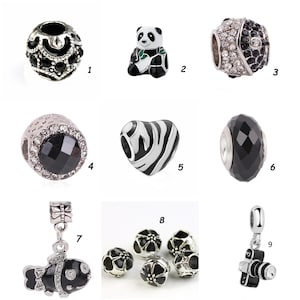 May include: A collection of charm beads in various designs. Includes a black and silver filigree bead, a panda bear, a bead with clear and black crystals, a black faceted bead, a zebra heart, a fish, flower beads, and a camera charm.