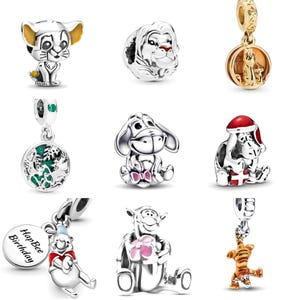 May include: A collection of silver charm beads featuring characters from Disney's The Lion King and Winnie the Pooh. The charms include Simba, Mufasa, Eeyore, and Tigger, with some charms featuring colorful accents and holiday themes.