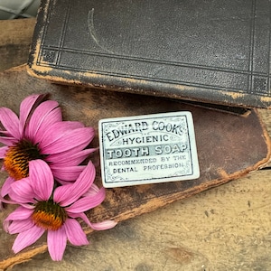 May include: A vintage white ceramic tile with black lettering advertising "Edward Cook's Hygienic Tooth Soap" and the text "Recommended by the Dental Profession."
