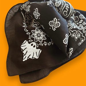 May include: Black bandana with a white ghost and paisley pattern.